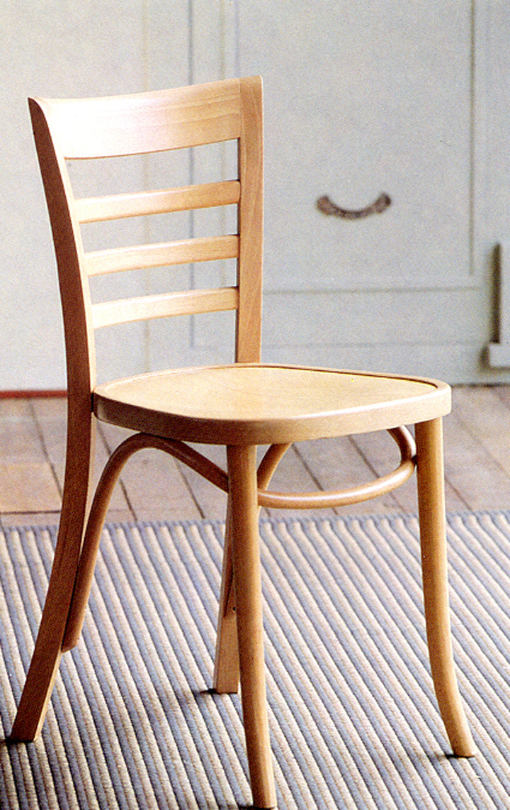 A natural beech wooden chair with slatted back on a wooden floor with rug 