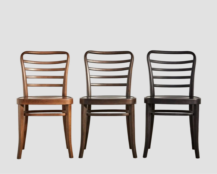 Three wooden chairs with slatted backrests in different finishes on a light wooden floor.