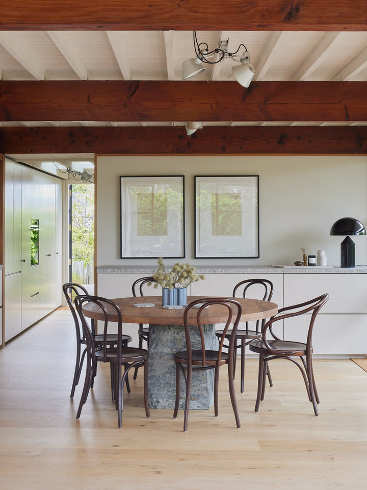 Dark oak bentwood dining chairs with curved backrest around a round table in a contemporary house