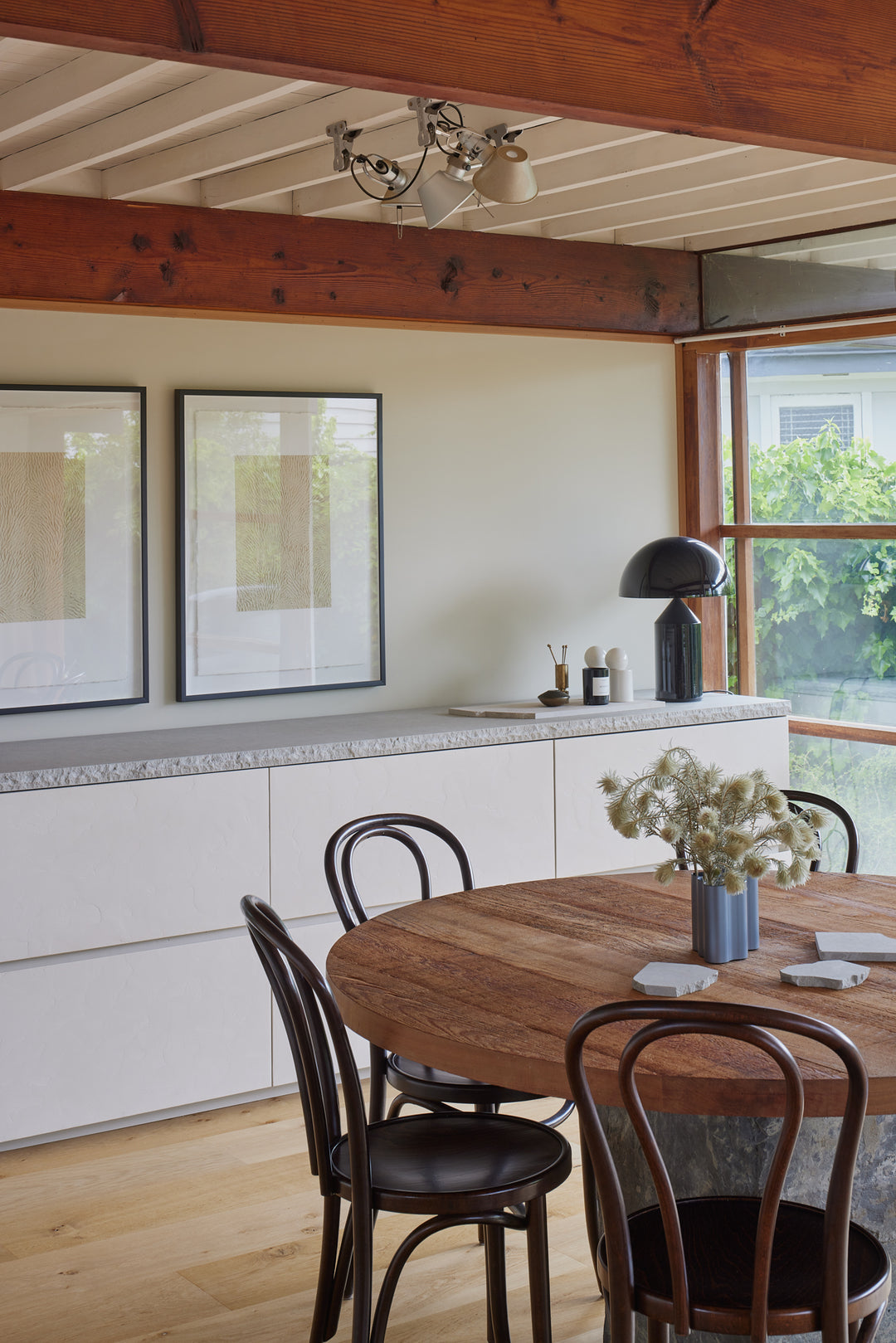 Dark oak bentwood dining chairs with curved backrest around a round timber table in a contemporary house